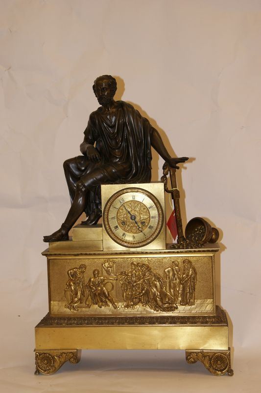Orologio da tavolo sec. XIX, in metallo dorato con figure in altorilievo sulla base e sovrastante uomo seduto