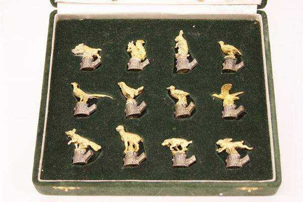 Dodici segnaposto, in metallo argentato e dorato , raffiguranti animali entro custodia