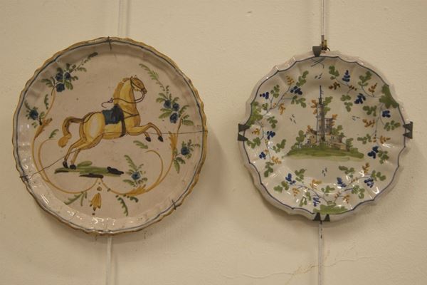 Due piatti, sec. XIX, in maiolica decorata a paesaggi e animale, cm 24-28, presenta restauri e difetti