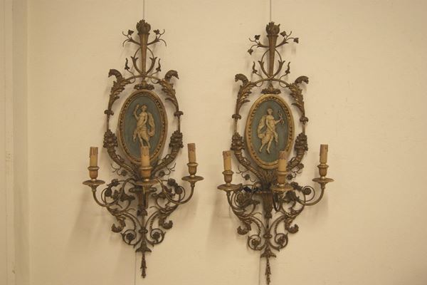 Coppia di appliques, stile settecento, in metallo e legno decorato con al centro bassorilievi ovali raffiguranti personaggi, a tre luci cm 92x42, difetti