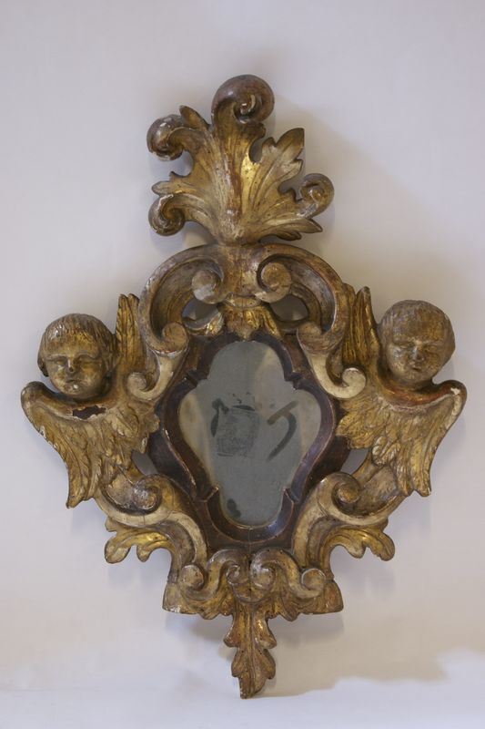 Specchierina, sec. XIX, in legno dorato  e intagliato, con ai lati testine di putti, cm 66x47, difetti  - Asta Arredi e Oggetti d'Arte, Mobili e Dipinti Antichi - Poggio Bracciolini Casa d'Aste