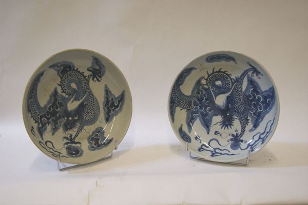Coppia di piatti, Cina sec. XIX,in porcellana bianca con decori a draghi blu, diam. cm 28