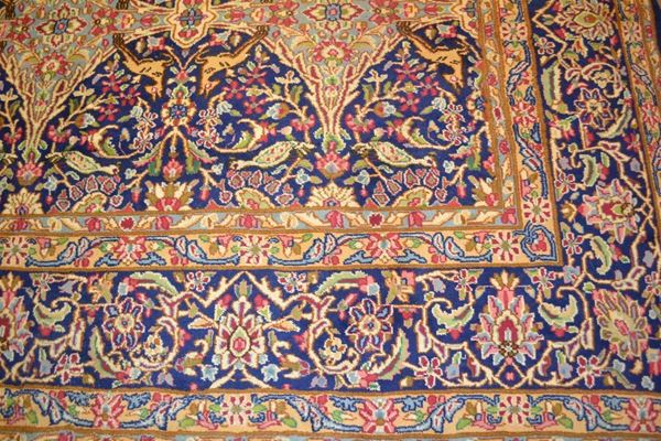 Grande tappeto, Kirman, Persia, 1920 circa, fondo azzurro decorato da motivi romboidali tra tralci vegetali e volatili nei toni del rosa, azzurro e blu, cm 300x356