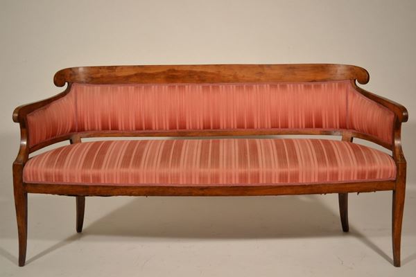 Divano a pozzetto, Toscana, inizi sec. XIX, con schienale imbottito, sormontato da fascia liscia e ricurva, braccioli lievemente mossi, gambe a sciabola, rivestito in stoffa rossa a righe