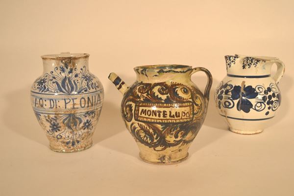 Brocca, sec. XIX, in maiolica bianca con decoro nei toni del blu e cartiglio con iscrizione in corsivo AQ.DI PEONIA, alt. cm 24 ed una brocca, sec.  XIX, in maiolica bianca con decoro floreale nei toni del blu, alt. cm 21, ed un orciolo, sec. XIX, in maiolica, beccuccio a pippio e cartiglio con iscrizione MONTELUPO, alt. cm 22 (3)