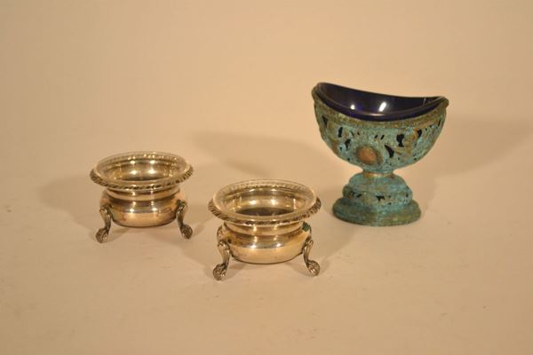 Gruppo, secc.XIX-XX: coppia di piccole saliere circolari in argento con bordo rovesciato baccellato e con coppette in vetro ed una saliera a barca in argento cesellato con puttini e coppetta in vetro(3)