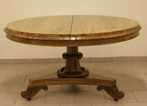 Tavolo tondo, sec. XIX, in noce con gamba centrata intagliata con base a tripode, piano a vela, cm 139x76, danni sul piano