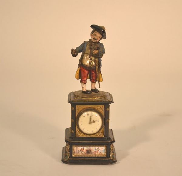 Originale orologio con quadrante sormontato da figura di gobbo realizzato in madreperla e metallo a smalti policromi poggiante su base con placchette in smalti  a scenette di genere, alcuni lievi  danni