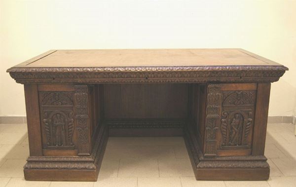 Scrivania da centro, Inghilterra, sec. XIX, in rovere riccamente intagliato, piano in cuoio, due sportelli, tre cassetti, cm 180x105x82