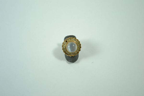 Anello in oro giallo a corolla con pietra di  luna cabochon circolare e piccole pietre di cui  una mancante, gr. 9