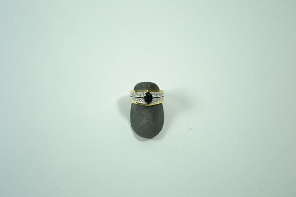 Anello in oro giallo con zaffiro ovale scuro affiancato da due linee di piccolissimi brillanti  montati in oro bianco, gr. 7