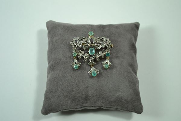 Spilla pendente in oro giallo e argento modellata a scudo traforato a volute decorato in  smeraldi e rose di diamante, gr. 11