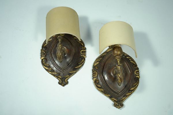 Sette appliques, in stile Settecento, in noce intagliato e lumeggiato oro, parte centrale a scudo in cornice a volute, braccio in ferro battuto con  foglie di acanto, complete di applicazione elettrica e paralume (7)