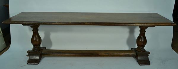 Grande tavolo, in stile Seicento, in noce, piano rettangolare con becco di civetta, sostegni torniti a balaustra, piedi a ciabatta riuniti da traverse, cm 278x73x80