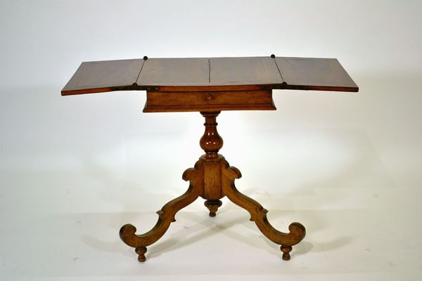 Tavolino, sec. XIX, in noce e radica di noce, piano quadrato da aprirsi, fusto a balaustro su tre piedi sagomati, aperto cm 106x54x72