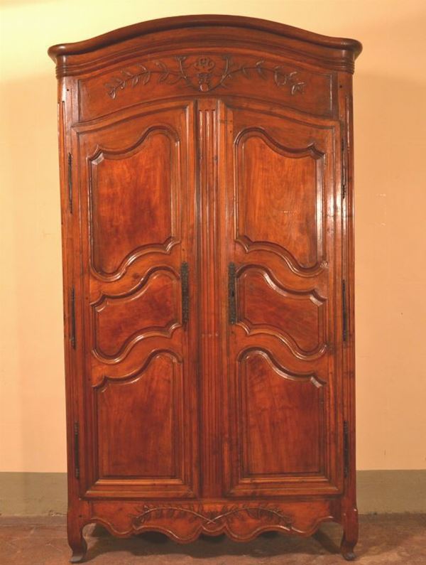 Armadio,  in noce e legno dolce a due sportelli intagliati a riserve  sagomate, gambe mosse, cm 140x65x250
