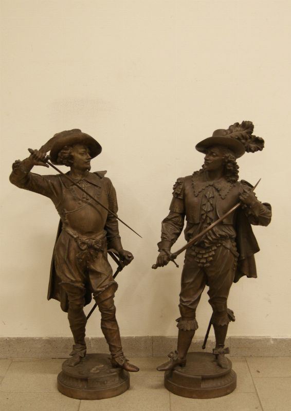 Coppia di sculture, sec. XX, in metallo dorato, raffigurante MOSCHETTIERI, alt. cm  90 e cm 95