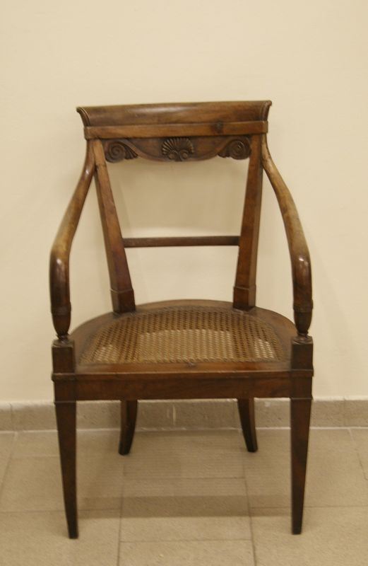 Poltroncina, Liguria, metÃ  sec. XIX, in noce intagliato, spalliera curvilinea con cartella a volute contrapposte, braccioli torniti a giorno su sostegni a vaso, gambe troncopiramidali, sedile in cannetÃ©