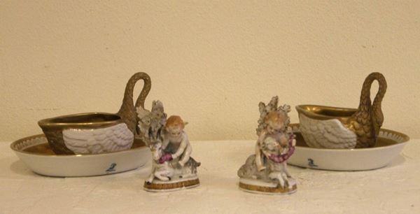 Coppia di tazze in forma di cigni con piattini ovali in porcellana di Desdra in parte dorata;  Coppia di piccole figure di puttini policromi,  probabilmente Germania sec. XIX-XX (6)