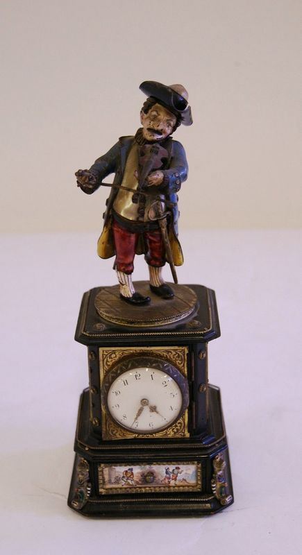 Originale orologio, con quadrante sormontato da figura di gobbo realizzato in madreperla e metallo a smalti policromi, poggiante su base, con placchette in smalti a scenette di genere, alt. cm 22, danni