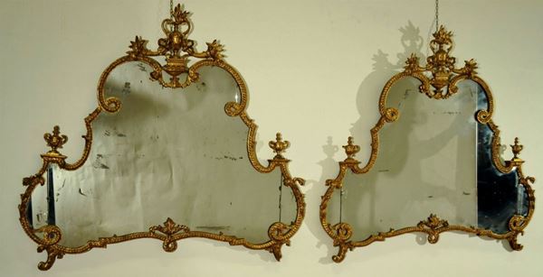Coppia di caminiere, in stile Settecento, in legno intagliato e dorato di forma sagomata, cimasa a vaso fra cornucopie, cornice a tortiglione, piedia ricciolo, cm 110x125, alcuni danni e mancanze (2)