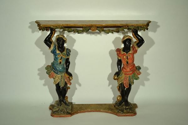 Piccola console, in legno intagliato e dipinto, piano sagomato dipinto a finto marmo giallo con pendaglina a festone vegetale sorretto da due mori di gusto veneziano, cm 98x22x81, alcune cadute di colore