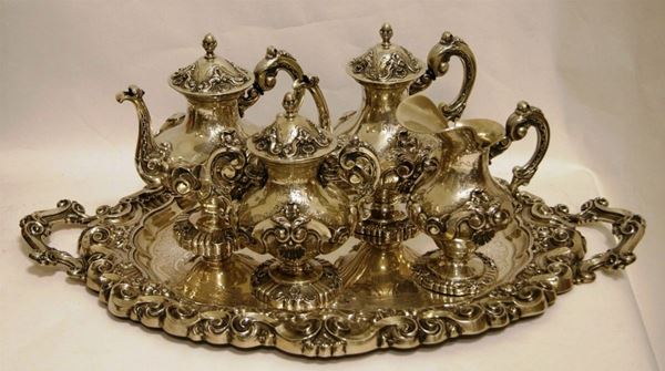 Servito da thÃ¨ e caffÃ¨, Portogallo, metÃ  sec. XX, in argento, composto da teiera, caffettiera, lattiera, zuccheriera e vassoio, dal corpo riccamente sbalzato a motivi vegetali, di conchiglie e volute e cesellato a motivi fogliacei stilizzati, manici a volute vegetalifogliacei stilizzati, manici a volute vegetali, presa sbalzata a motivo fogliaceo, vassoio di forma ovale dal bordo e manici sbalzati a elementi vegetali a voluta con piatto cesellato, per complessivi gr. 5650