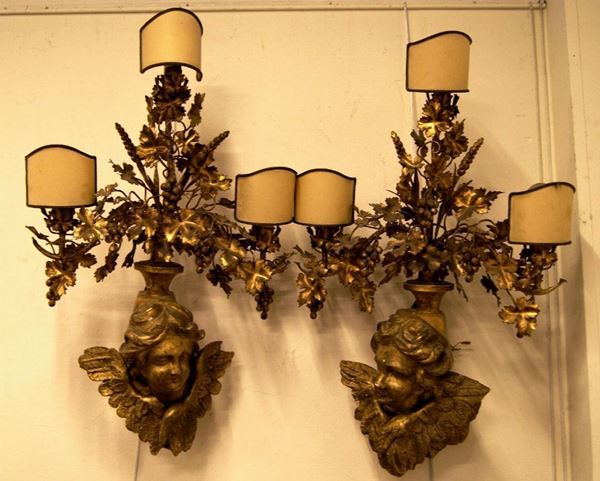 Coppia di applique, sec. XIX, in legno e metallo dorato, con teste di putti a tre luci, cm 85x55 (2)
