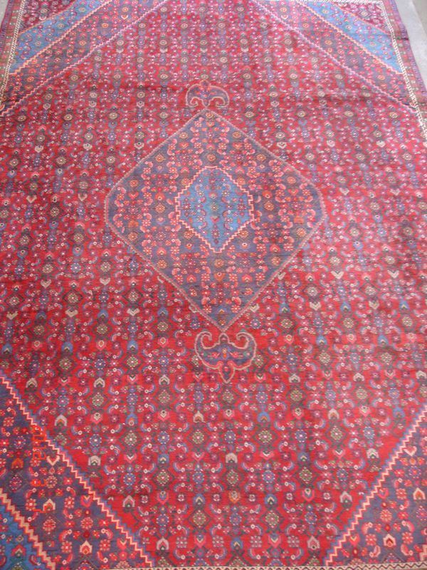 Tappeto persiano Meime di vecchia manifattura, campo a motivo geometrico e fiori stilizzati, fondo rosso, medaglioni e bordura celeste, cm 340x237