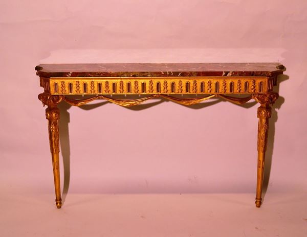 Console, in stile Luigi XVI, in legno intagliato e dorato, piano in breccia di marmorosa, pendaglina intagliata a festone, gambe scanalate, cm 140x41x87