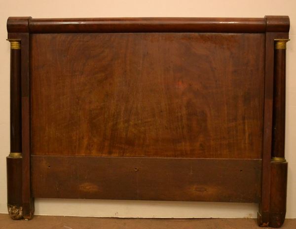 Letto, epoca Impero, in noce, testiera inquadrata da colonne con capitelli in bronzo dorato, piedi a plinto, cm 196x149, lievi danni