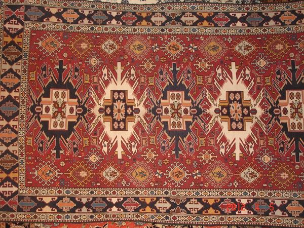 Tappeto caucasico sumak, di vecchia manifattura, fondo rosso, campo a motivo geometrico e fiori stilizzati, con cinque medaglioni e bordura multicolore cm 205x128