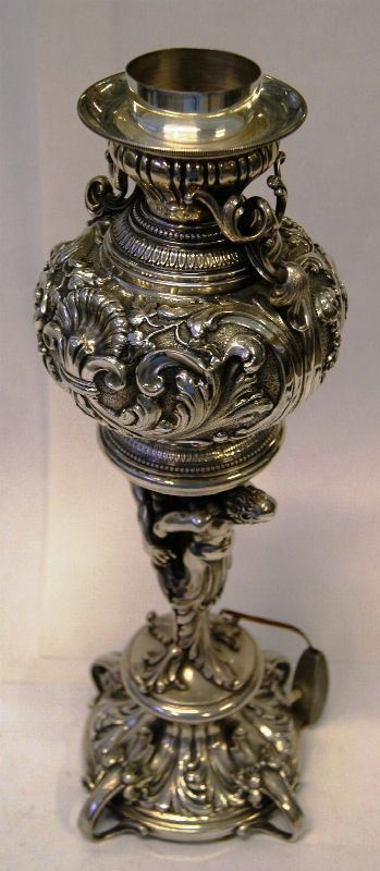 Lume da tavolo, in argento, riccamente decorato a elementi vegetali e figure maschili, alt. cm 42,5, gr. 1550 lordi