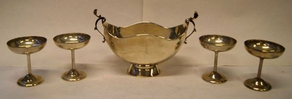 Centrotavola, in argento, rialzato su base ovale, piccoli manici a volute, cm 28x14x17, e Quattro coppette, in argento, alt. cm 11, gr. 835(5)