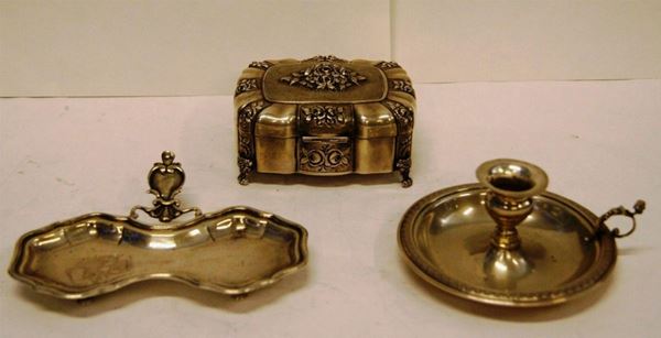 Lotto composto da: portagioie, in argento, cesellato a rose; bugia, in argento, e posa occhiali, in argento sagomato, poggiante su quattro piedini rotondi, dimensioni portagioie cm 12x10x6, complessivi gr. 400 lordi(3)