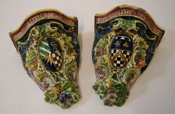 Coppia di mensoline, Toscana, sec. XX, in maiolica decorata, con stemma e fiori in altorilievo, cm 15x19, piccoli difetti(2)