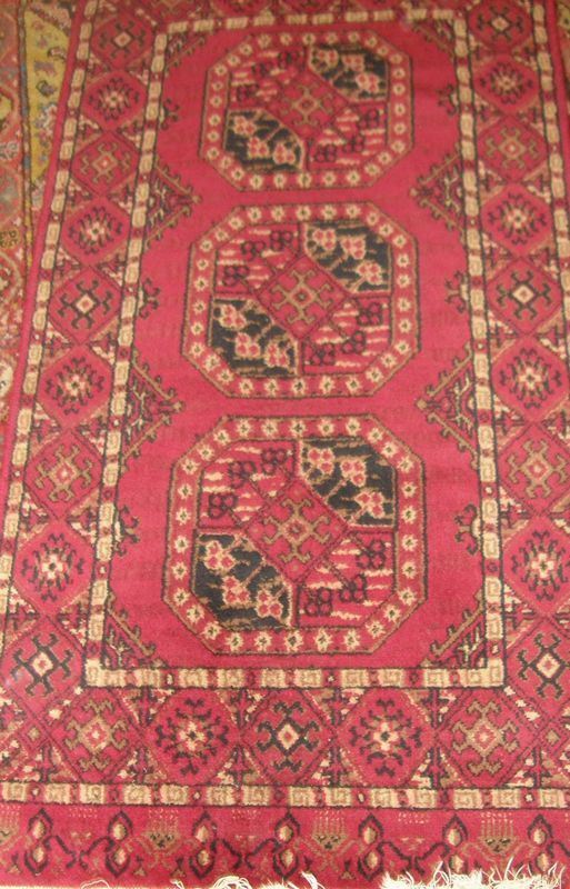 Tappeto pedana fondo rosso, al centro tre elementi ottagonali nti toni del  rosso e del nero, bordura ad elementi dentellati e profili avorio, cm       67x142