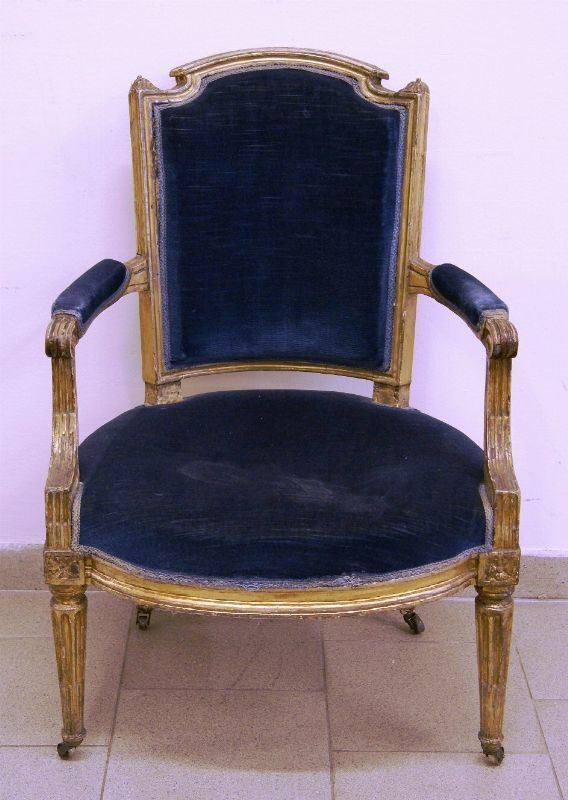 Poltrona, fine sec. XVIII, in legno intagliato e dorato, imbottita e ricoperta in velluto blu, quattro piedi a colonne scanalate su ruote, alt. cm 88