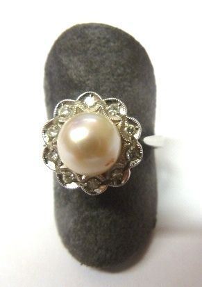 Anello in oro bianco, perla e diamanti                                      al centro una perla coltivata montata entro una cornice decorata da dieci   piccoli brillanti, g  4