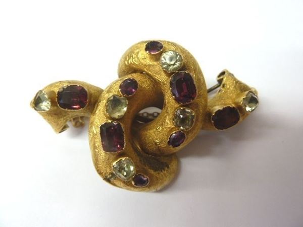 Spilla in oro giallo e pietre semipreziose                                  modellata come un nodo in oro cesellato impreziosito da pietre              semipreziose, g 14