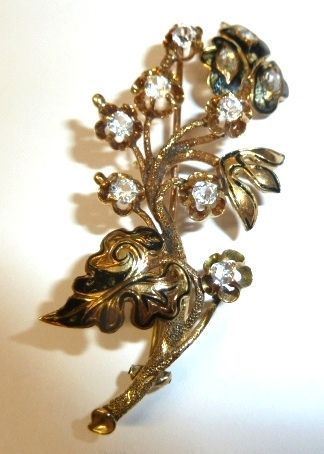 Spilla in oro giallo e pietre ad imitazione del diamante                    modellata a tralcio di fiori e foglie decorati da smalti e pietre ad        imitazione del diamante, g 11, smalti danneggiati
