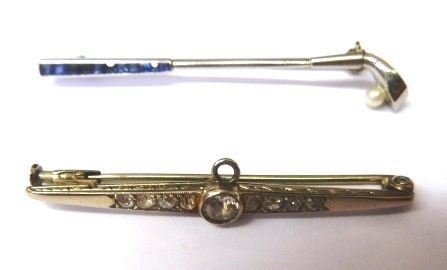 Spilla in oro bianco, zaffiri e perla                                       modellata come una mazza da golf, il manico decorato da piccoli zaffiri, la pallina realizzata con una microperla e    Spilla in oro bianco e diamanti                                             realizzata come una barretta decorata da una linea di piccolissimi          brillanti di taglio vecchio e centrata da un brillante di taglio vecchio    (2)