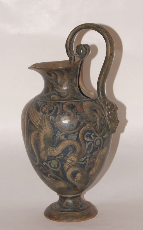 Brocca, in stile settecento,  in terraglia dipinta, manico a voluta e testa di putto, alt. cm 31