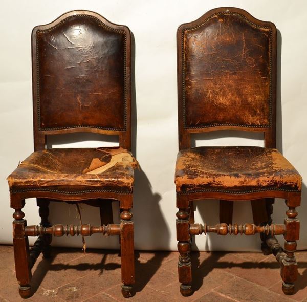 Coppia di sedie, in stile Seicento, con spalliera sagomata e gambe          rettilinee riunite da traverse tornite a rocchetto, ricoperte in cuoio, danni                        (2)