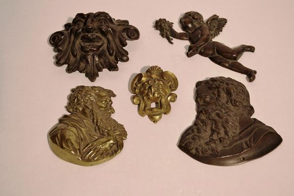 Gruppo di placchette in bronzo e bronzo dorato, secc. XVII-XIX, composto    di: placchetta, in bronzo dorato, sagomato a profilo di MosÃ¨ cm 11,5x9;     placchetta, in bronzo sagomato a profilo di MosÃ¨ reca fori per              applicazioni, cm 12,5x12; una placchetta, in bronzo modellata a putto       alato, alt. cm 17; placchetta, in bronzo cesellato a mascherone tra volute  fogliacee ed una bocchetta in metallo dorato modellata a mascherone, cm     7,5x6 (5)
