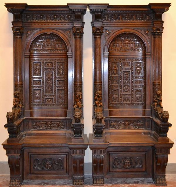 Coppia di stalli di coro in stile Cinquecento, in noce riccamente           intagliato, braccioli a volute con putti scolpiti a tutto tondo, piedi a    zampa ferina (2)