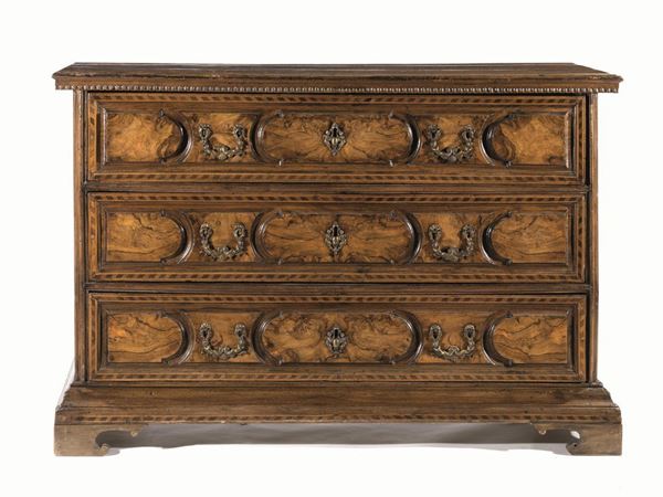 Cassettone, Emilia, metÃ  sec. XVII, in noce a patina bionda e radica pianorettangolare con gocciolatoio sotto al piano, fronte a tre cassetti decorati da formelle lobate con specchiature in radica e bordo intarsiato a nastrino, base modanata, piedi a mensola, cm 149x63x98, piedi di restauro