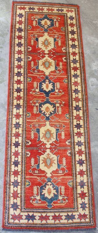 Tappeto ghazny, con colori vegetali naturali, fondo rosso, campo a motivo geometrico e fiori stilizzati a medaglioni vari multicolori, bordura beige, cm 260x82