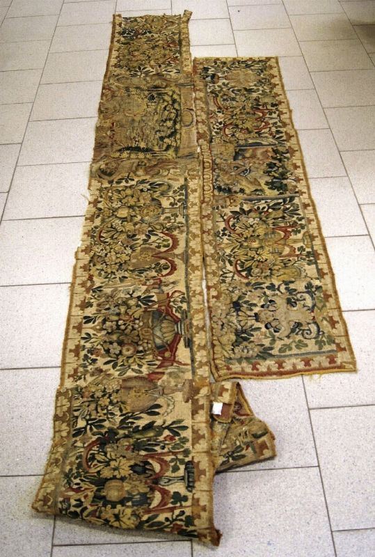 Due frammenti di arazzo, sec. XVI, decorati a paesaggi, vasi di fiori e figure, lunghezza cm 420 e cm 175, difetti (2)
