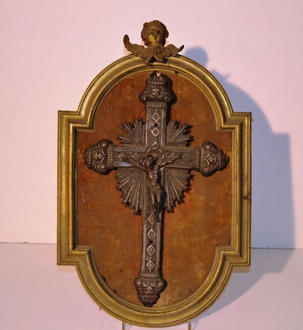 Crocefisso in metallo argentato, secolo XIX, montato su pannello entro cornice in bronzo dorato, cm 30x20